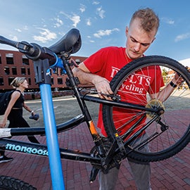 Trent Hohenstreiter works on a bike behind the MCSC.