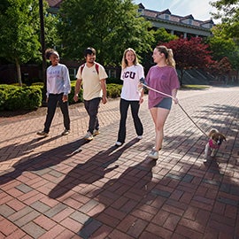 ECU students walking on campus with dog.