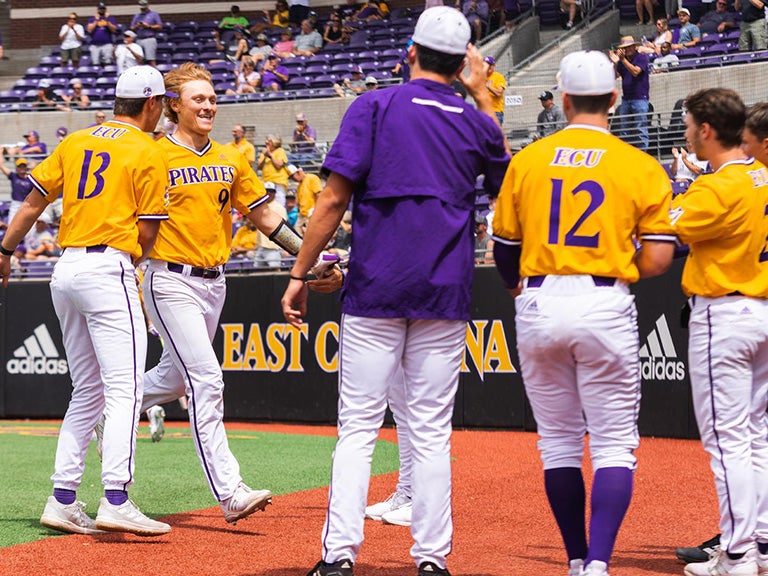 ECU baseball team members meet at pitcher's mound.